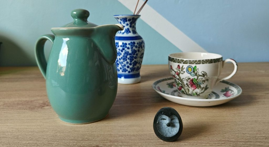 A teal Denby teapot, an Indian Tree pattern cup and saucer, and a small stone hedgehog ornament