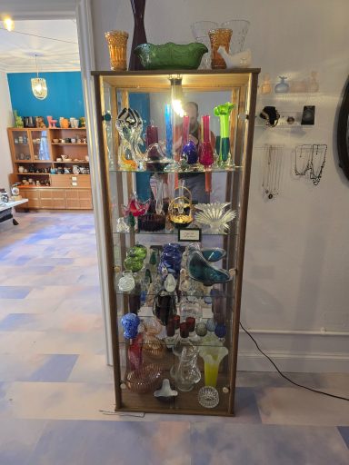 A glass display cabinet filled with various colourful decorative items and figurines.