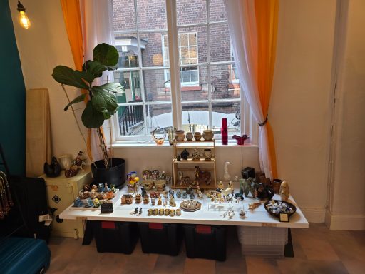A display of various decorative items and trinkets on a table by a window.