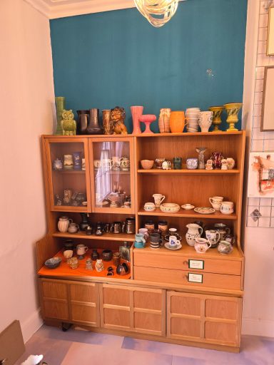 Display of various decorative ceramics and collectibles on a wooden shelving unit.