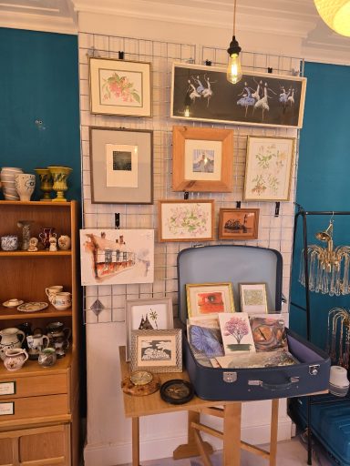 A display of framed art and vintage items on a wall with a blue background.